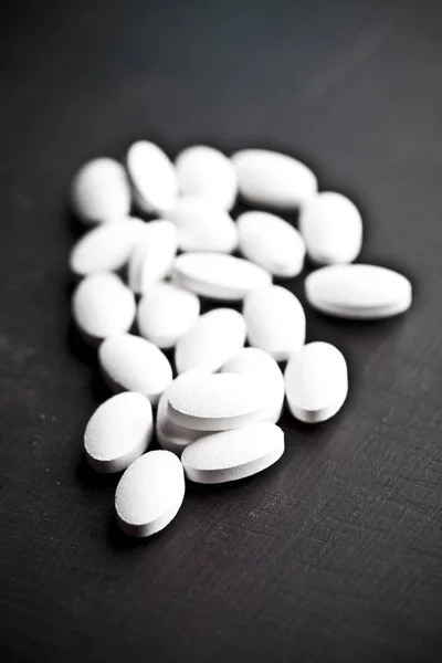 Stapel weißer Medikamententabletten auf schwarzem Hintergrund. — Stockfoto