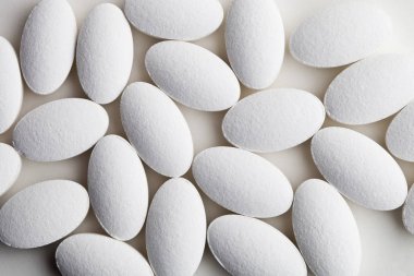 Beyaz arka plan üzerinde yatan beyaz ilaç yığını.