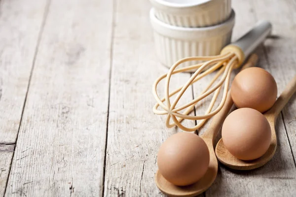 Čerstvé kuřecí vejce a kuchyňské nádobí na rustikálním dřevěném stole ba — Stock fotografie