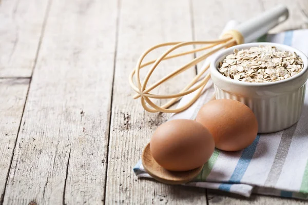 Huevos de pollo frescos, copos de avena en tazón de cerámica y utensilios de cocina —  Fotos de Stock