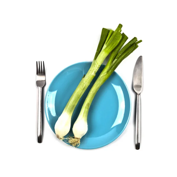 Organic green onion on blue plate, fork and knife on white backg — Stock Photo, Image