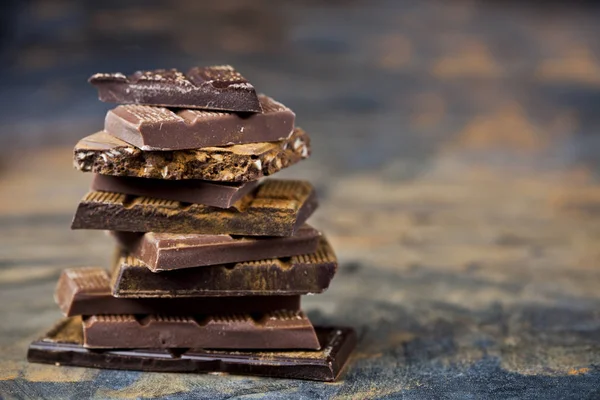 黒い背景に積み重ねられた壊れたチョコレート。チョコレートバーのピック — ストック写真