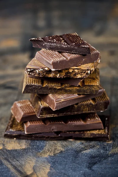 黒い背景に積み重ねられた壊れたチョコレート。チョコレートバーのピック — ストック写真