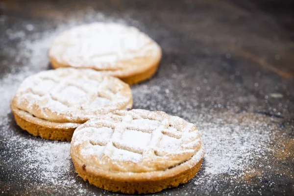 Fresh baked tarts with chocolate filling and sugar powder on bla — Stock Photo, Image