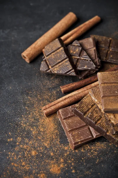 Chocolate bar pieces heap witn cinnamon powder and sticks. Broke — Stock Photo, Image