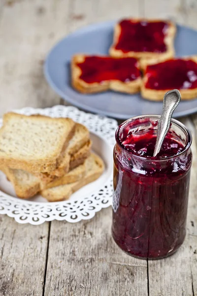 Homemade cherry jam and fresh toasted cereal bread slices plates — Stock Photo, Image