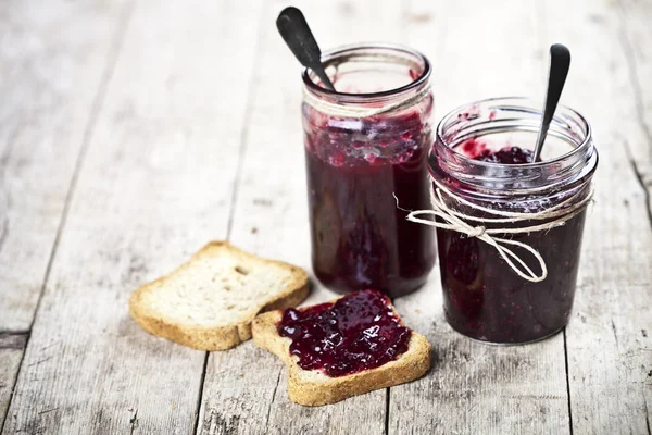 Toasted cereal bread slices and jars with homemade wild berries — Stock Photo, Image