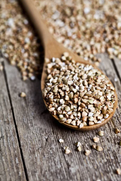 Organic green dry buckwheat seads in wooden spoon closeup on rus — Stock Photo, Image