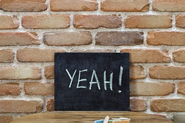 Chalk board with the word YEAH! drown by hand and chalks on wood — Stock Photo, Image