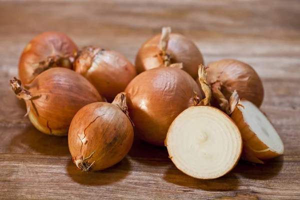 Biologische verse uien heap close-up op rustieke houten tafel. — Stockfoto