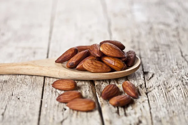 Organic fresh almond seeds on wooden spoon closeup on rustic woo — Stock Photo, Image