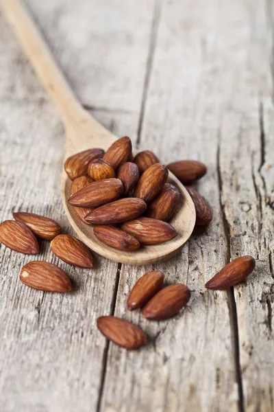 Organic fresh almond seeds on wooden spoon closeup on rustic woo — Stock Photo, Image