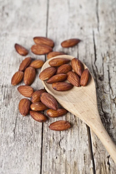 Semillas frescas de almendras crudas sobre cuchara de madera primer plano sobre madera rústica —  Fotos de Stock