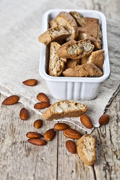 Cookies cantuccini in white ceramic bowl and almond seeds on lin — Stock Photo, Image