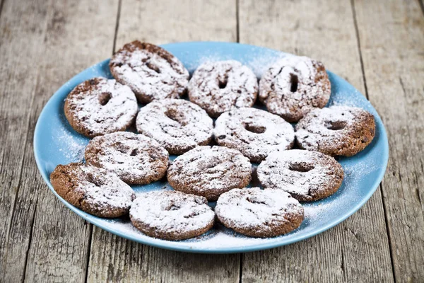 Mavi pla üzerinde toz şeker ile taze pişmiş çikolatalı kurabiye — Stok fotoğraf