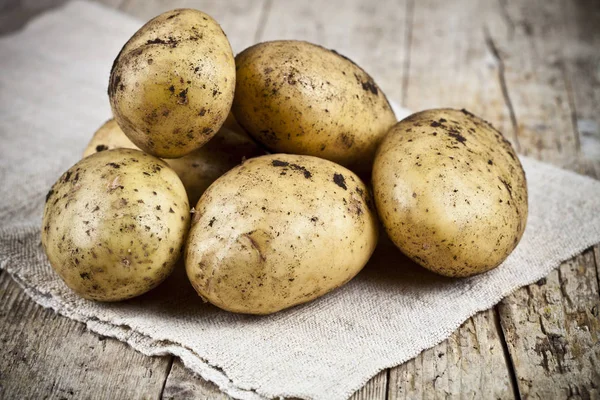 Fresh organic dirty potatoes heap closeup on linen tablecloth on — Stock Photo, Image