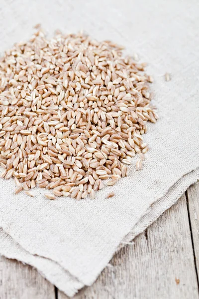 Dry raw organic wheat grain heap on linen tablecloth on rustic w — Stock Photo, Image