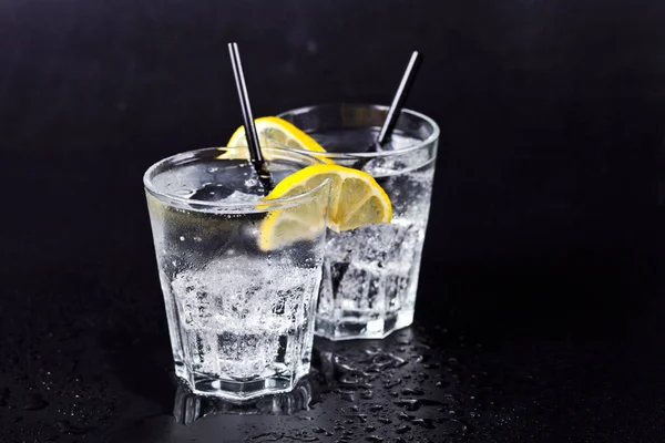 Two glasses of fresh cold carbonated water with ice cubes and le — Stock Photo, Image