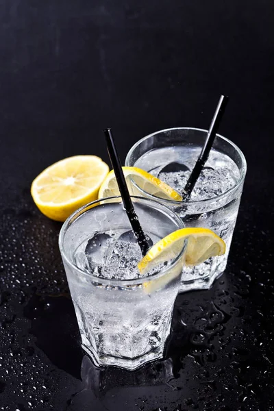 Two glasses of fresh cold carbonated water with ice cubes and le — Stock Photo, Image