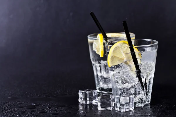Glas frisches kaltes kohlensäurehaltiges Wasser mit Eiswürfeln und Zitronensl — Stockfoto