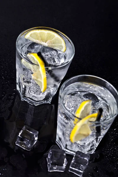 Bicchieri di acqua fresca fredda gassata con cubetti di ghiaccio e limone — Foto Stock