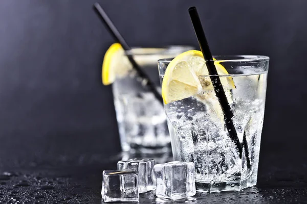 Glasses of fresh cold carbonated water with ice cubes and lemon — Stock Photo, Image