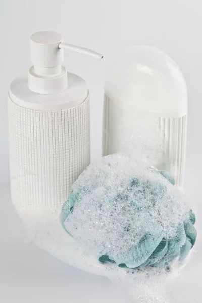 Liquid soap, lotion, green sponge and foam on light background. — Stock Photo, Image