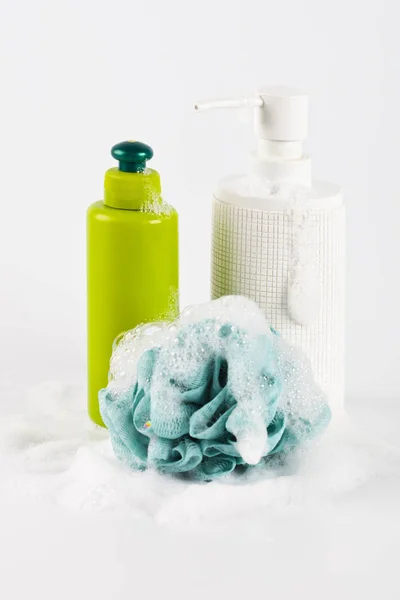 Bath cosmetic products, green sponge and foam on light backgroun — Stock Photo, Image