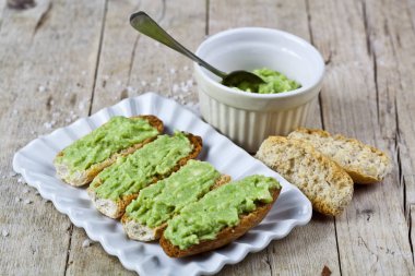 Rustik üzerinde beyaz plaka çekim üzerinde avokado guacamole ile crostini