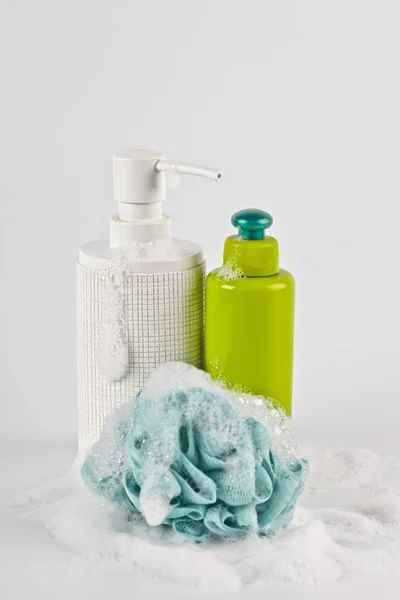 Bath cosmetic products, green sponge and foam on light backgroun — Stock Photo, Image