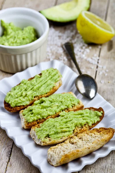 Torradas com guacamole abacate na placa branca closeup em rústico w — Fotografia de Stock