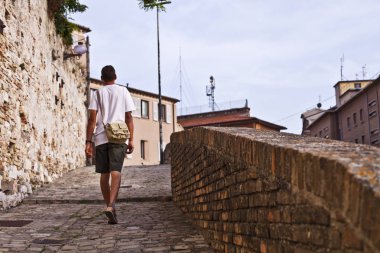 Antik kentte yürüyen bir adamın arka görünümü.