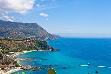Turkuaz körfezi, kumlu sahil, yeşil dağlar ve bitkiler, mavi gökyüzü beyaz bulutlar arka plan, uçurum platformu Capo Vaticano Cape, Calabria, Güney İtalya.