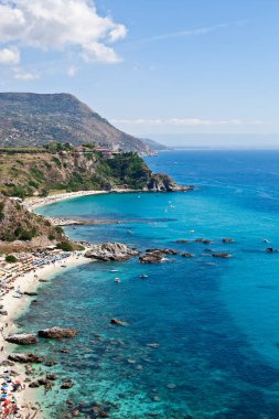 Turkuaz körfezi, kumlu sahil, yeşil dağlar ve bitkiler, mavi gökyüzü beyaz bulutlar arka plan, uçurum platformu Capo Vaticano Cape, Calabria, Güney İtalya.