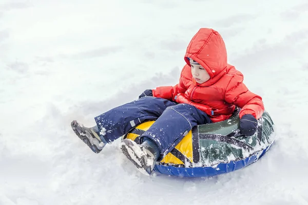 Boy with the inflatable sledge, snow tube, inner tube, lies on snow