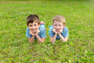 Yedi yaşındaki İkizler çim, yaz aylarında çim üzerinde yalan