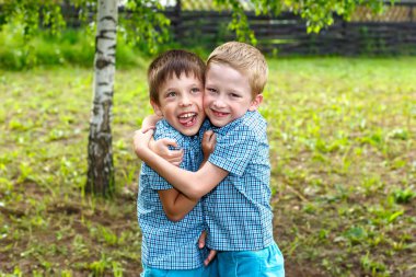 Yedi yaşında ikiz erkek yaz güneşli bir günde kucaklama