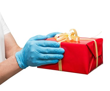 Teslimatçı eleman, mavi cerrahi eldivenli, elinde hediye kutusu var. Paylaşım, verme veya teslim etme kavramı. Beyazda izole edilmiş. Servis karantina pandemik koronavirüs virüsü.