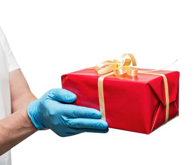 Teslimatçı eleman, mavi eldivenli, elinde hediye kırmızı kutu var. Paylaşım, verme veya teslim etme kavramı. Beyazda izole edilmiş. Servis karantina pandemik koronavirüs virüsü.