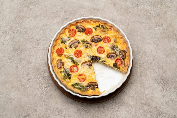 Baked homemade quiche pie in ceramic baking form on concrete background — Stock Photo, Image