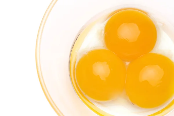 Três gemas de ovo em uma tigela de vidro isolada em fundo branco — Fotografia de Stock