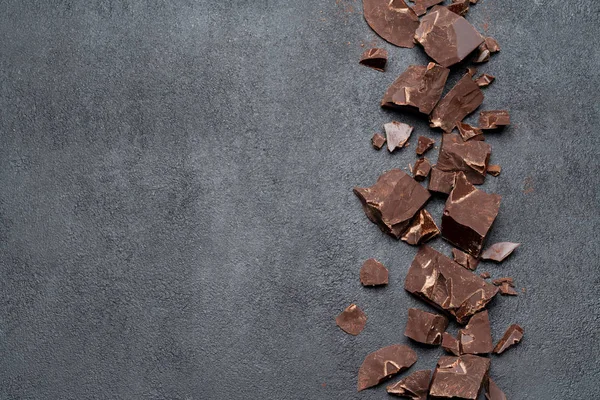 Telaio o bordo realizzato con pezzi di cioccolato biologico fondente o al latte su backgound in cemento scuro — Foto Stock