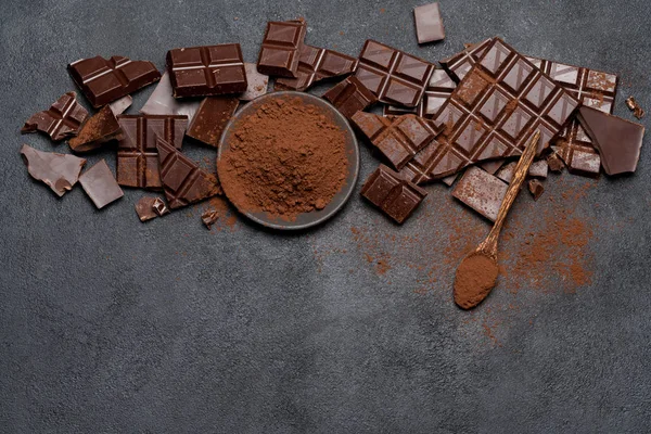 Telaio o bordo realizzato con pezzi di cioccolato fondente o al latte biologico e cacao in polvere su backgound in cemento scuro — Foto Stock