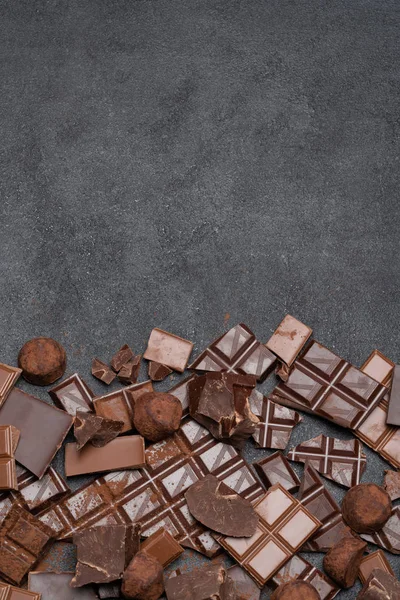 Morceaux de chocolat bio noir ou au lait, poudre de cacao et bonbons à la truffe sur fond de béton noir — Photo