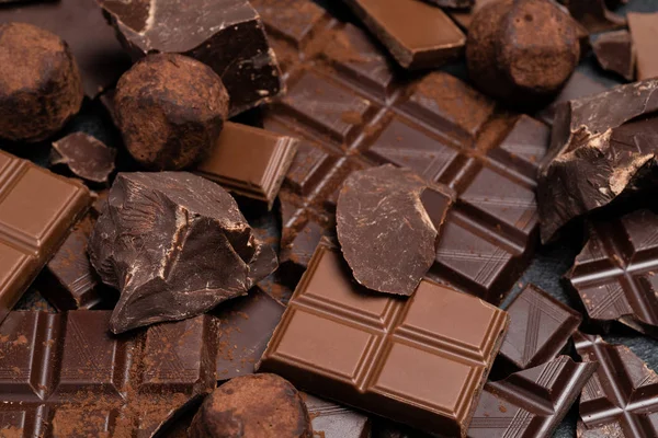 Тёмный или молочный органический шоколад, какао-порошок и трюфельные конфеты на темно-бетонном фоне — стоковое фото