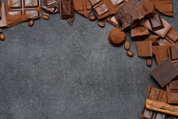 Dark or milk organic chocolate pieces, cocoa powder and truffle candies on dark concrete backgound