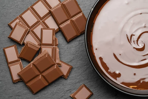 Keramikschale mit Schokoladencreme oder geschmolzener Schokolade und Schokoladenstücken isoliert auf dunklem Betonhintergrund — Stockfoto