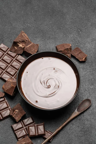 Keramische kom van chocolade crème of gesmolten chocolade en stukjes chocolade geïsoleerd op donkere betonnen achtergrond — Stockfoto