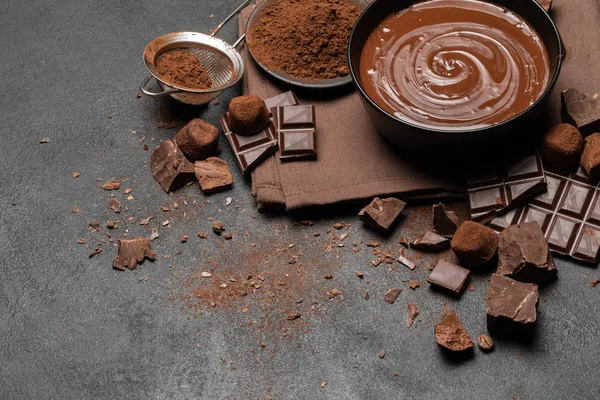 Tazón de cerámica de crema de chocolate o chocolate derretido y trozos de chocolate aislados sobre fondo de hormigón oscuro — Foto de Stock