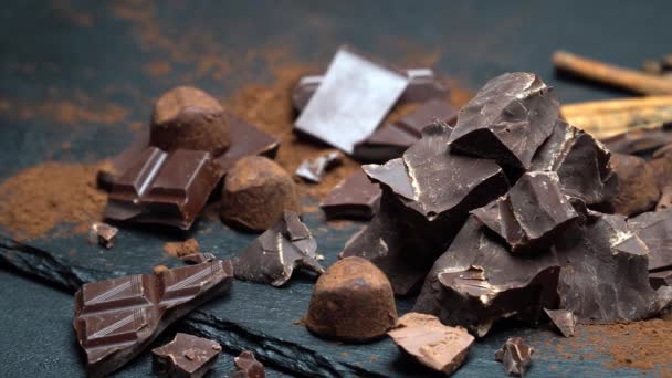 Pezzi di cioccolato fondente o al latte biologico e cacao in polvere su sfondo di cemento scuro — Video Stock